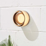 Arden ceramic wall light with a warm amber glow on a white brick wall