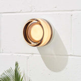 Arden ceramic wall light with a warm amber glow on a white brick wall