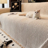 Fairford herringbone sofa cover draped over a corner sofa with a cat resting on it