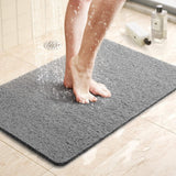 Milton non slip grey loop shower mat on a bathroom floor with water draining through