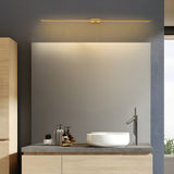 Wystan slim linear LED wall light in gold above a bathroom mirror and basin