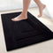 Orwell soft microfibre non slip bath mat in black on a bathroom floor
